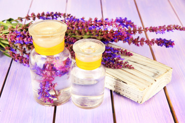 Medicine bottles with salvia flowers on purple wooden