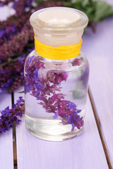 Obraz na płótnie Canvas Medycyna butelki z Salvia kwiatów na fioletowym tle drewniane