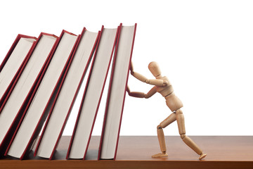 Figurine stopping a domino effect caused by falling books