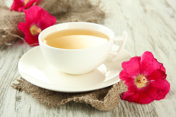 Cup of tea and pink mallow flowers on wooden background