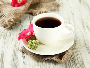 Cup of coffee and pink mallow flowers on wooden background