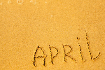 April - written in sand on beach texture