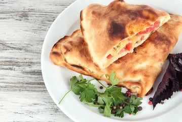 Pizza calzones on plate on wooden table