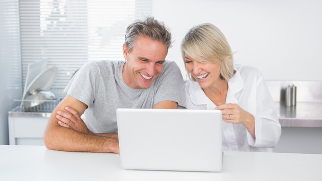 Happy Couple Laughing At Laptop In The Morning