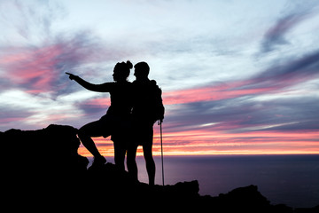 Couple hikers silhouette in mountains