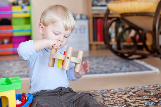 Little toddler boy playing with wooden toys
