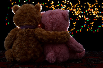 Two Teddie bear sitting holding bokeh background