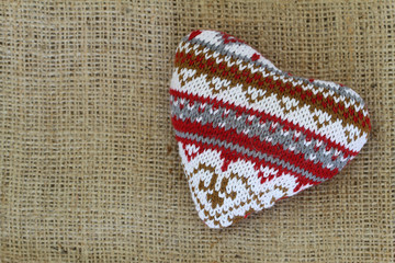 Fototapeta na wymiar Knitted heart on jute background with copy space