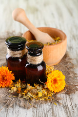 Medicine bottles and calendula flowers on wooden background