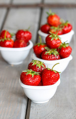 Fresh ripe strawberries in white ceramic bowls