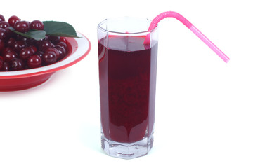 Cherry juice with a straw and fresh cherries in the background