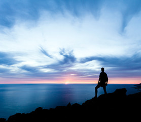Man hiking silhouette in mountains, ocean and sunset