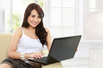 young asian woman sitting in sofa using a laptop