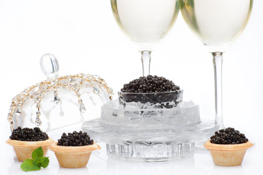 Black caviar and champagne in glass on a white
