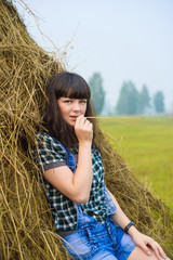 Portrait of pretty brunette lying on haystack