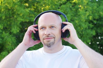 happy man listening music outdoors in wireless headset