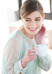 Portrait of a young woman smiling and enjoying a cup of coffee