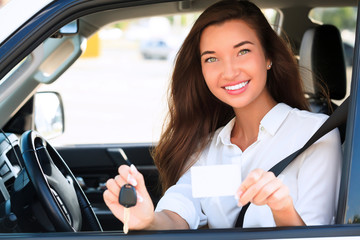 Fototapeta na wymiar girl in a car showing a key and an empty white card