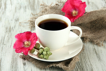Cup of coffee and pink mallow flowers on wooden background