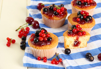 Tasty muffins with berries on white wooden table