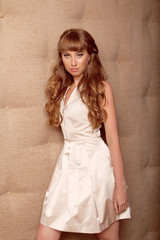 Fototapeta premium Brown Hair. Beautiful girl with long Curly Hair leaning on the w