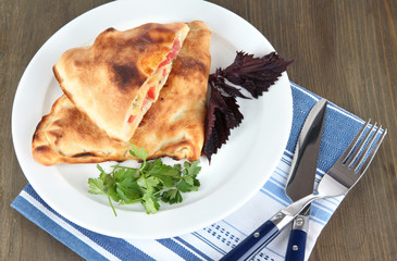 Pizza calzone on plate on napkin on wooden table
