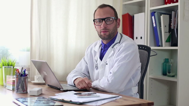 Friendly doctor talking to camera in the office