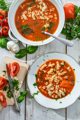 Tomato soup with noodle and ingredients on old wooden table