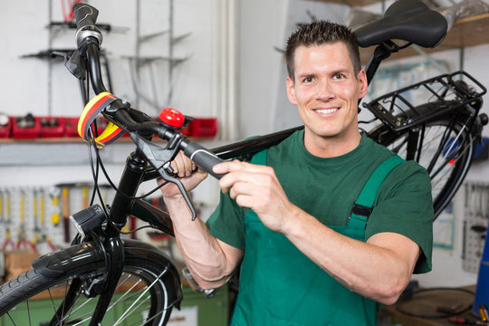Bicycle mechanic carrying a bike in workshop