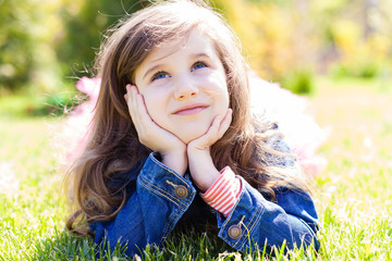 cute little girl lying on the grass in summertime