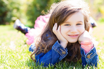 cute little girl lying on the grass in summertime