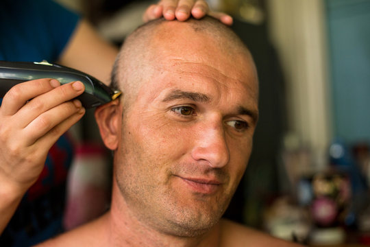 Hairdresser makes hairstyle bald man.