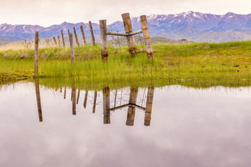 Old wooden fence reflection in the water of a marsh - Powered by Adobe