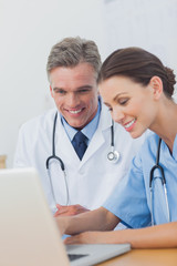 Two cheerful doctors working on a laptop