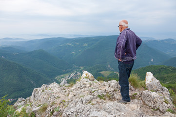 Senior man standing on top of a mountain