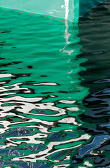 Green hull of a boat with reflection in the water