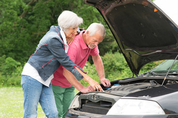 Senior couple at broken car