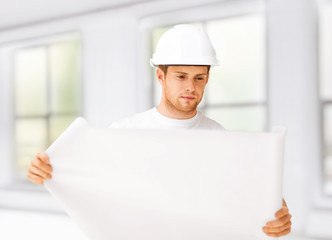 male architect looking at blueprint at home