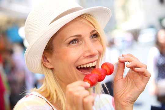 Cheerful blond girl eating fresh fruits in summer