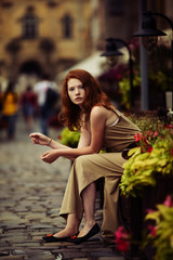 beautiful red-haired woman resting on the streets of the beautif