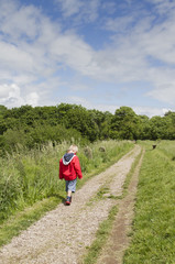 Obraz premium Young blond boy walking along canal towpath
