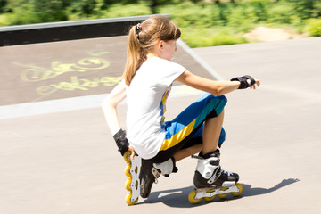 Teenage girl in rollerblades crouching down