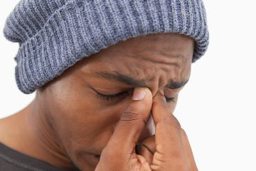 Man in beanie hat wincing with a headache