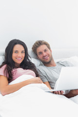Fototapeta premium Couple using a laptop in bed