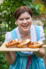 Happy beautiful woman in dirndl dress holding pretzel