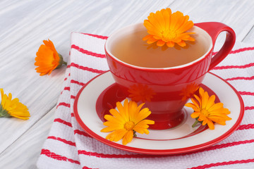 Calendula flower tea on striped tablecloth on the table
