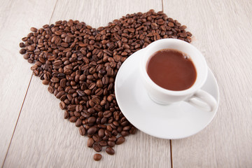 Heart of coffee beans with a cup