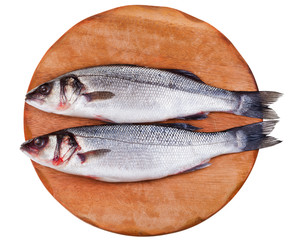 two raw seabass on wooden board