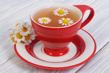 herbal tea with chamomile flowers in a red cup