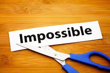 Word impossible cut to possible over wood background